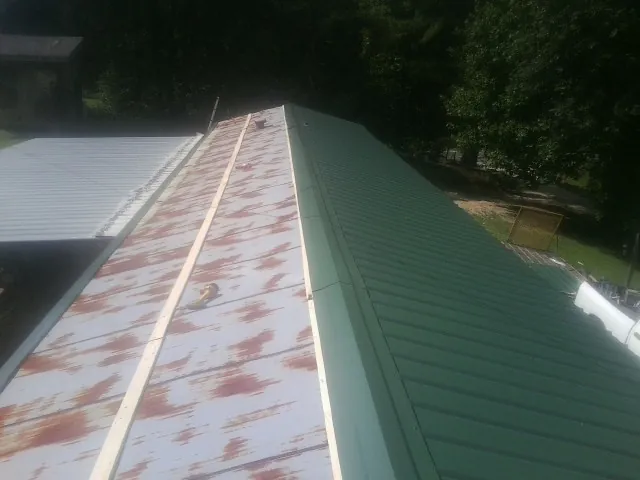 Old rusted panels beside newly installed green metal roofing — Wind Damage Roof Repair by Roofing Brothers in Wheeling