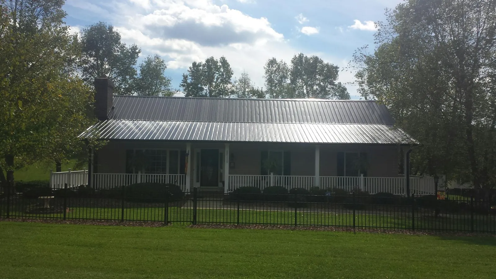 Gray metal roof on a brick ranch with a full width front porch — Gutter Guard Installation work by our crew in Wheeling