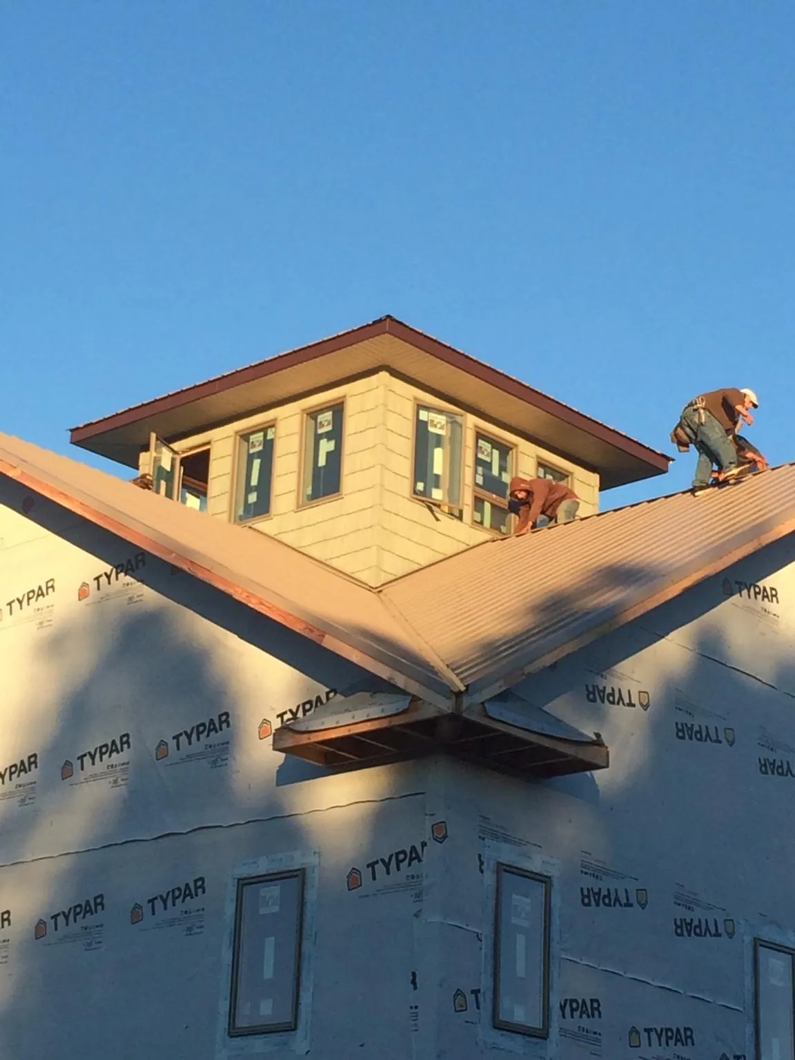 Roofers working around a rooftop cupola on a new metal roof at sunset — Roof Waterproofing in Wheeling by Roofing Brothers